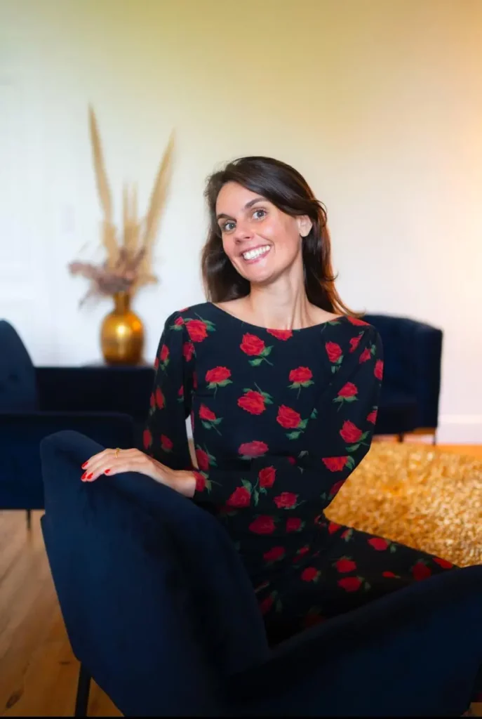 Louise poulin prof d'anglais pour entrepreneurs à toulouse assise sur un fauteuil bleu et souriant